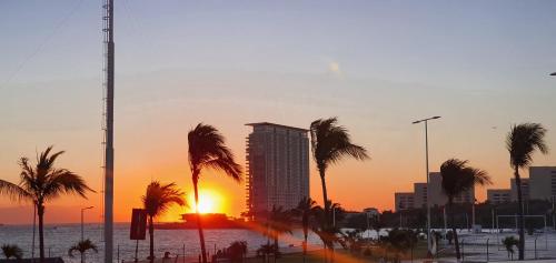 a sunset in a city with palm trees and a building at Loft 10 min from Oro &Holy Beach, Marina, Galerias in Puerto Vallarta