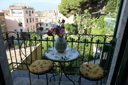 a vase on a table with two chairs on a balcony at Villa Gaia in Taormina