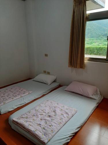 two twin beds in a room with a window at Song Lin Homestay in Dongshan