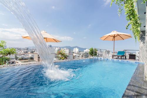 a swimming pool with a fountain and two umbrellas at Laurel Da Nang Apartment in Da Nang