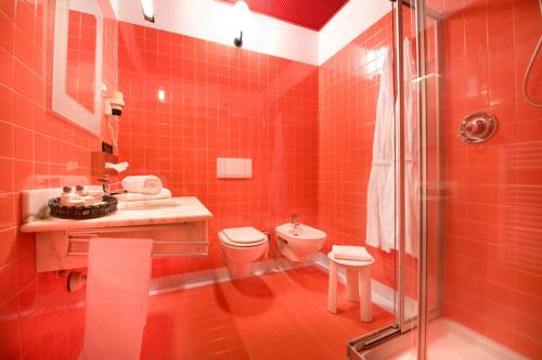 e bagno piastrellato rosso con servizi igienici e doccia. di Hotel Campelli a Sondrio