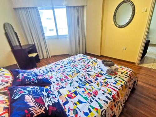 拉納卡的住宿－Flirty Flamingo Seaview Seafront Apartment，一间卧室配有一张带彩色毯子的床