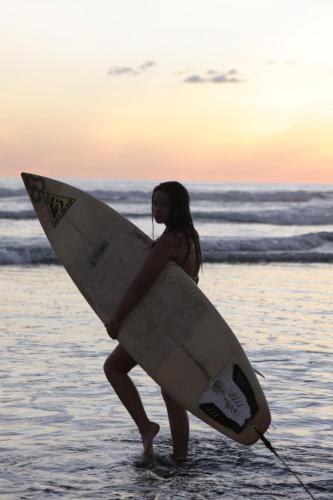 a woman walking in the water holding a surfboard at La Colina Pura Vista in Bejuco