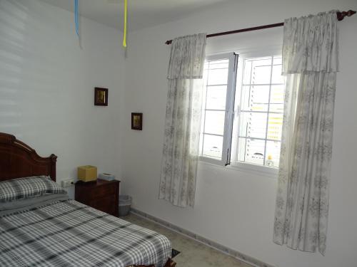 a bedroom with a bed and a window with curtains at Rickaty Lodge Bed and Breakfast, Airport Hotel, Hotel de aeropuerto, Las Palmas Airport, Gran Canaria Airport, LPA, Spain in Las Puntillas