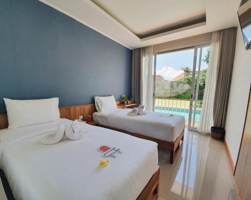 a hotel room with two beds and a window at RakaAyu Kuta in Kuta