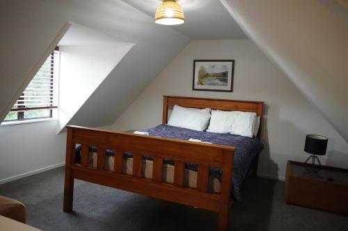 a bedroom with a wooden bed in a attic at Lazy Daze in Wanaka