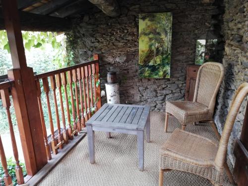 um alpendre com 2 cadeiras e uma mesa de madeira em Gîte Sainte Croix en Jarez, Le Val des Equins em Sainte-Croix-en-Jarez