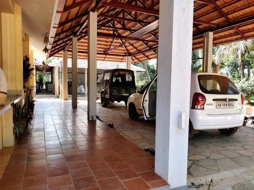 a building with two cars parked under a roof at Hanakodu homestay in Sringeri