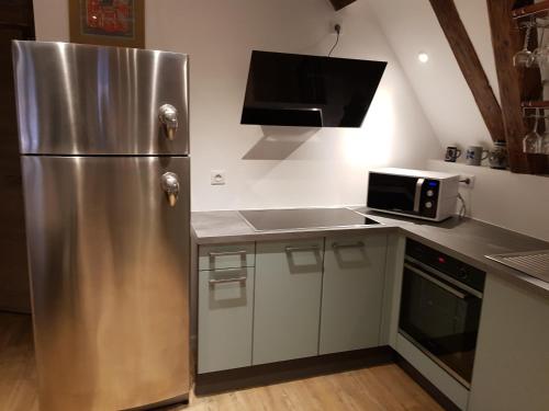 une cuisine avec un réfrigérateur en acier inoxydable et un micro-ondes dans l'établissement à l'orée du bois, à Riquewihr