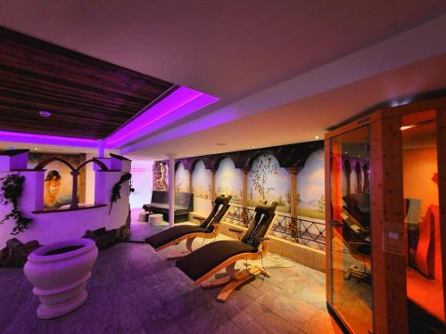 a room with some chairs and a wall with paintings at Hotel Lärchenhof in Lermoos