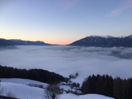 a view of a snow covered mountain with a foggy valley at Gruberhof in Rodengo