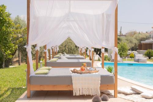 a bed with a canopy next to a pool at Skiathos Avaton Hotel, Philian Hotels & Resorts in Skiathos Town