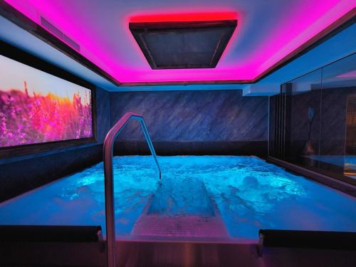 - un bain à remous dans une chambre avec des lumières roses dans l'établissement Alpen Appartements Lärchenhof, à Lermoos