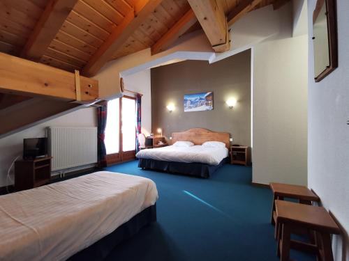 1 dormitorio con 2 camas en una habitación con suelo azul en Hotel Les Bruyères, en L'Alpe-d'Huez