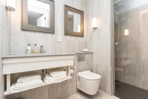 a bathroom with a sink and a toilet and a mirror at Hampton home B&B suites in De Koog