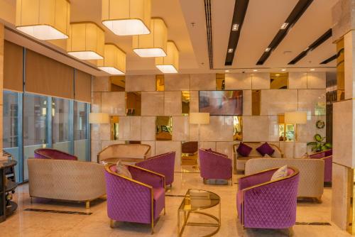 a lobby with purple chairs and a table at Royal Crown Hotel in Muscat
