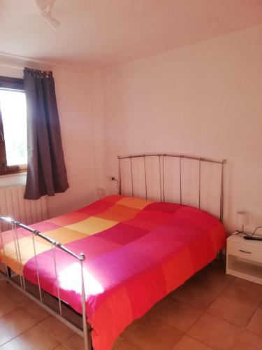 a bedroom with a bed with a colorful blanket at Villetta 3 km dal mare in Castagneto Carducci