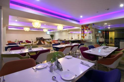 un restaurante con mesas y sillas blancas e iluminación púrpura en Best Western Ashoka, en Hyderabad