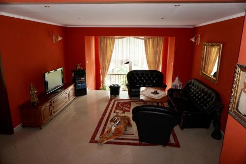 ein Wohnzimmer mit roten Wänden, schwarzen Stühlen und einem TV in der Unterkunft Penzion Vegas in Partizánske