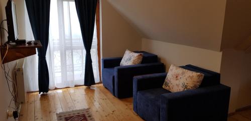 a living room with two blue chairs and a large window at Pensiunea Printul Vlad in Sibiel