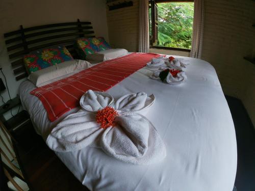 una cama con sábanas blancas y una flor en ella en Pousada Ibirapuera, en Jericoacoara