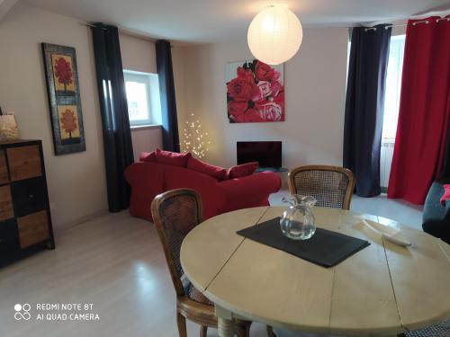 a living room with a table and a red couch at Gîte Les Gorges du Tarn in La Cresse