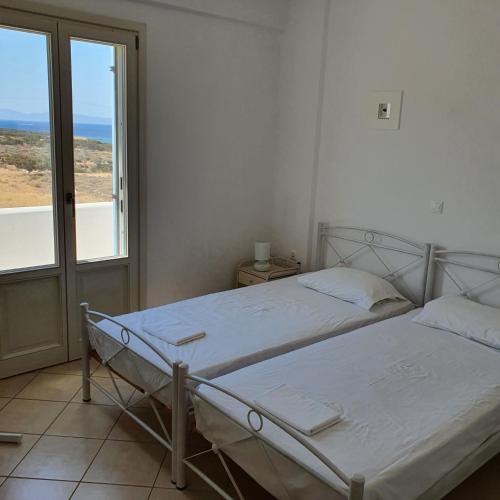 two beds in a white room with a window at Agiassos Naxos Apartments in Agiassos