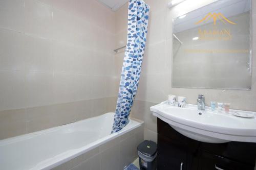 a bathroom with a sink and a toilet and a tub and a mirror at New Arabian Holiday Homes - Escan Tower in Dubai