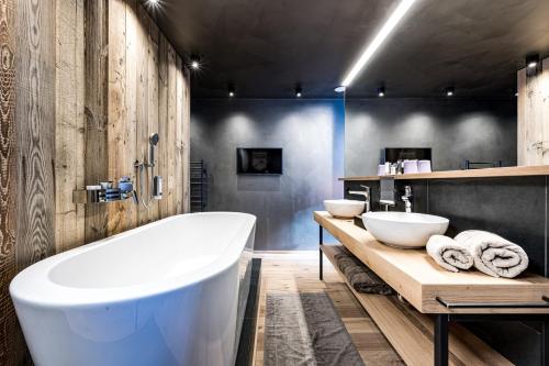 a large bathroom with two sinks and a tub at ALMMONTE PRÄCLARUM SUITES Design Hotel in Wagrain