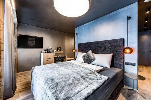 a bedroom with a large bed with a blue wall at ALMMONTE PRÄCLARUM SUITES Design Hotel in Wagrain