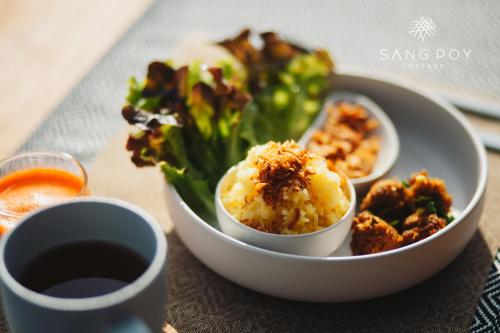 Sang Poy Cottage في Ban Kung Mai Sak: طبق من الطعام مع سلطة ووعاء من الطعام