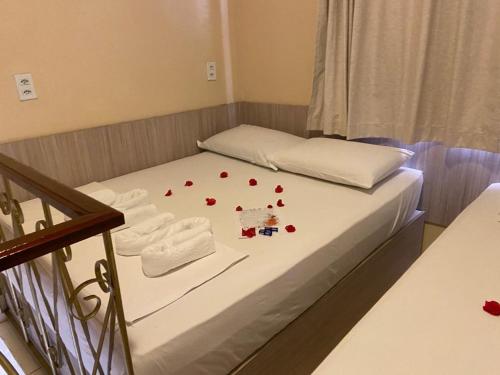 a bed with red rose petals on it at LINDO CHALÉ NO CENTRO DE GUARAMIRANGA in Guaramiranga