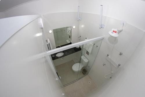 a white bathroom with a toilet and a mirror at Asturias Mall & Suítes in Guarujá