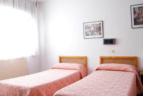 a bedroom with two beds and a window at Hostal Charo II in Santiago de Compostela