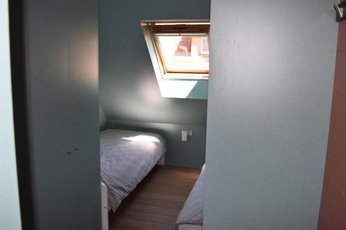 a small bedroom with a bed and a window at Oostduinkerke Apartments in Oostduinkerke