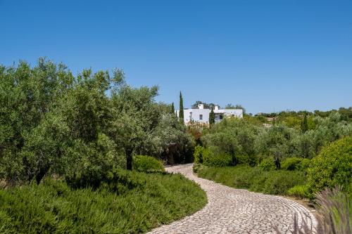 a gravel road with trees and a house in the background at Altanure Casa Terra - Ecological Boutique Stay in Tavira
