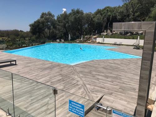 une grande piscine bleue avec une terrasse en bois dans l'établissement Résidence de Tourisme 5* Porto Vecchio, à Porto-Vecchio