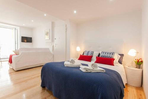 a white bedroom with a large bed with red pillows at Charming Studio in Mouraria in Lisbon