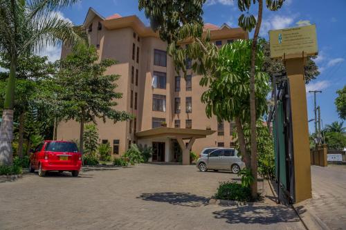 ein Gebäude mit Autos auf einem Parkplatz in der Unterkunft Panone Hotels - Sakina in Arusha