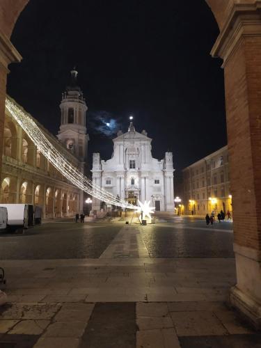 a large white building with a clock tower at night at Pensione Delfino Azzurro in Loreto
