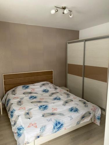 a bedroom with a bed with blue flowers on it at Апартамент в комплекс Смолянски езера in Smolyan