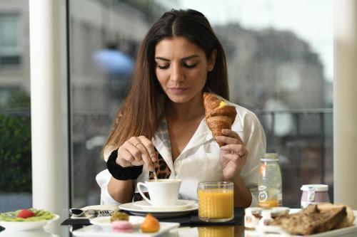 a woman sitting at a table eating a piece of food at The Street Milano Duomo | a Design Boutique Hotel in Milan
