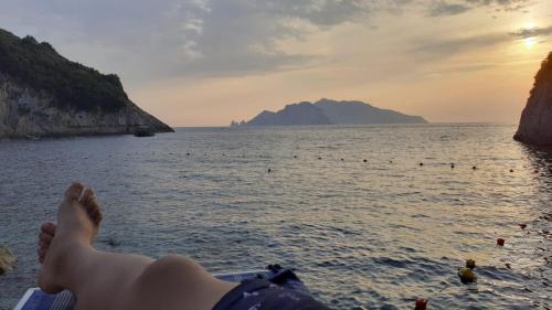 a person laying on the beach with their feet in the water at Emidio House in Termini