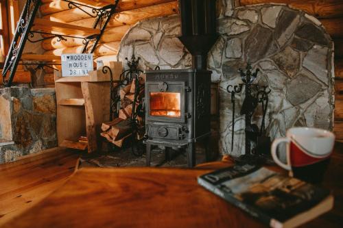 - un poêle à bois dans une chambre avec une table et un livre dans l'établissement Brvnara DRINA Wooden House Drina, à Drlače