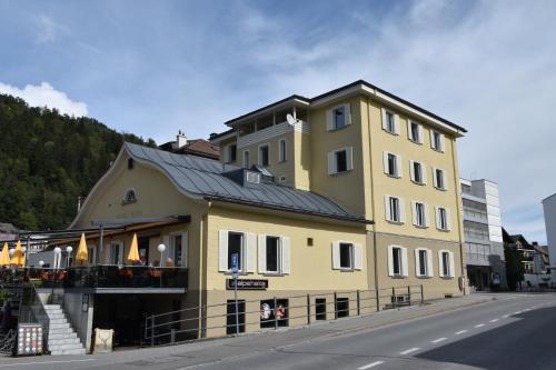 a yellow building with a black roof on a street at Hotel Rätia in Ilanz