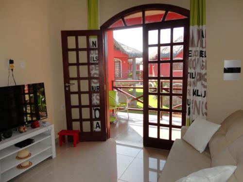 a living room with a door and a television at Chale Canoa Quebrada La Fazenda in Canoa Quebrada