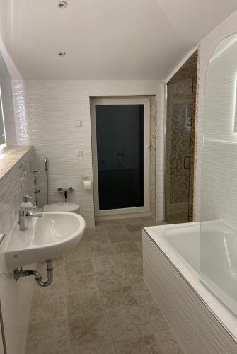 a white bathroom with a tub and a sink and a bath tub at Sleep2Fly Hamburg-Airport in Hamburg