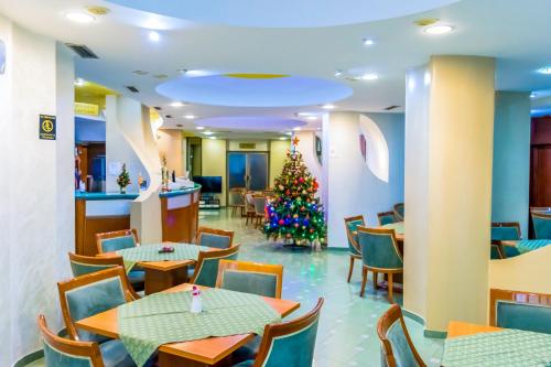 a christmas tree in a restaurant with tables and chairs at Hotel Cingo in Ohrid