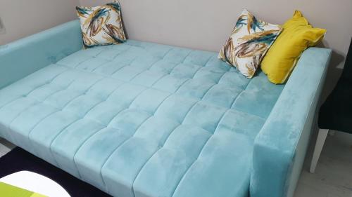 eine blaue Couch mit zwei Kissen darüber in der Unterkunft Apartman Sweet Dreams 3 in Niš