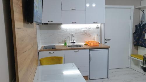 una piccola cucina con armadi bianchi e lavandino di Apartman Sweet Dreams 3 a Niš